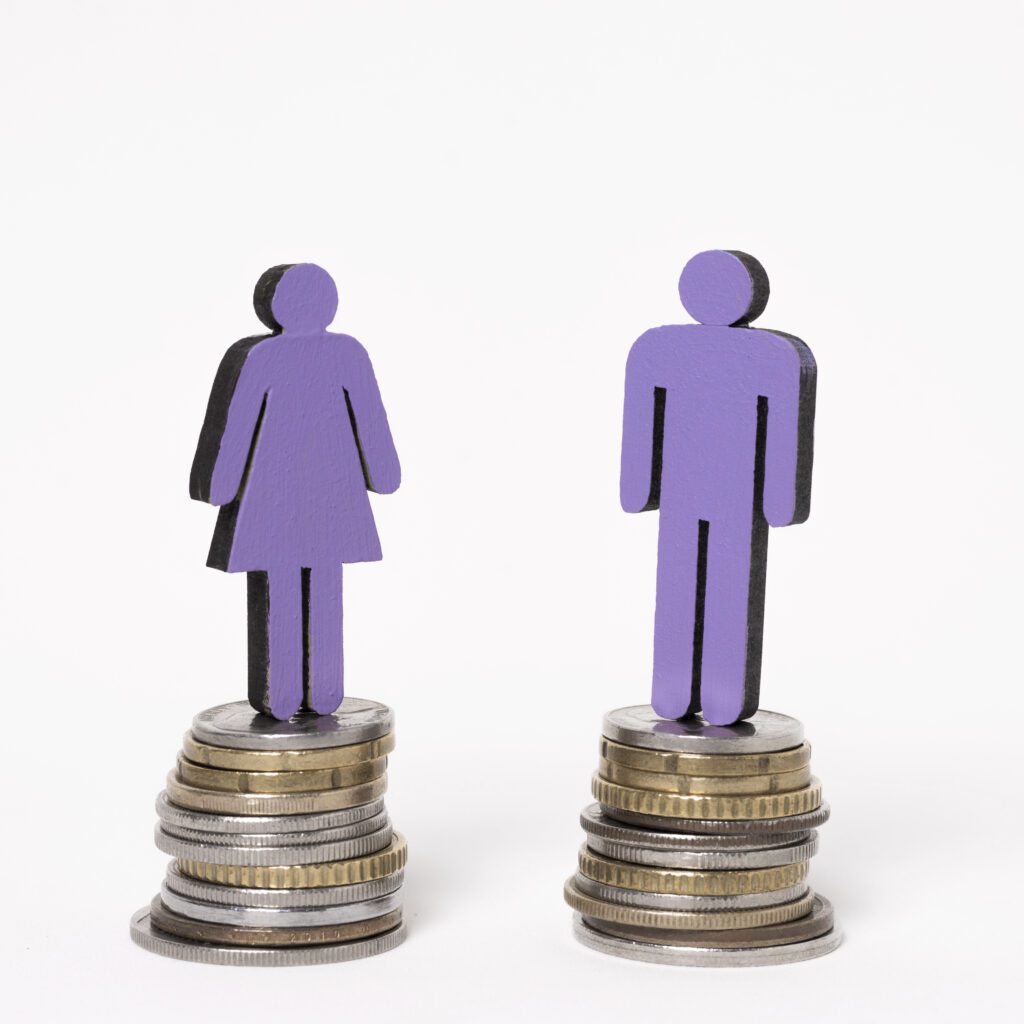 Igualdade salarial. Homem e mulher em pé em pilhas iguais de moedas. Foto: Freepik